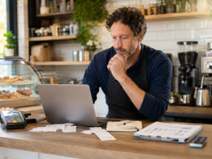 Café owner reviewing card sales and finance paperwork for business funding.