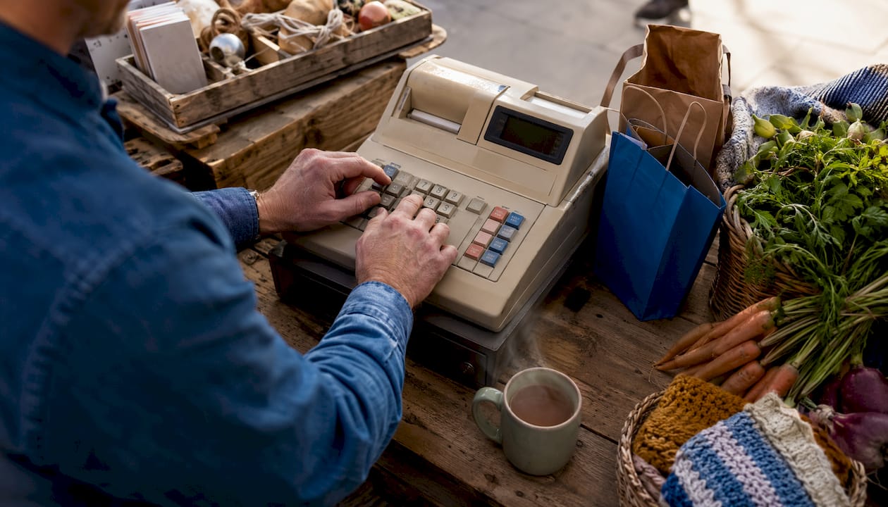 Hands using traditional till keypad in café