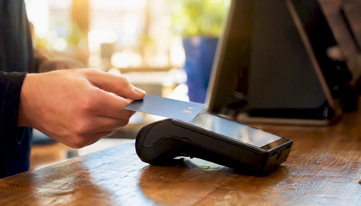 Hand tapping card payment terminal at retail till