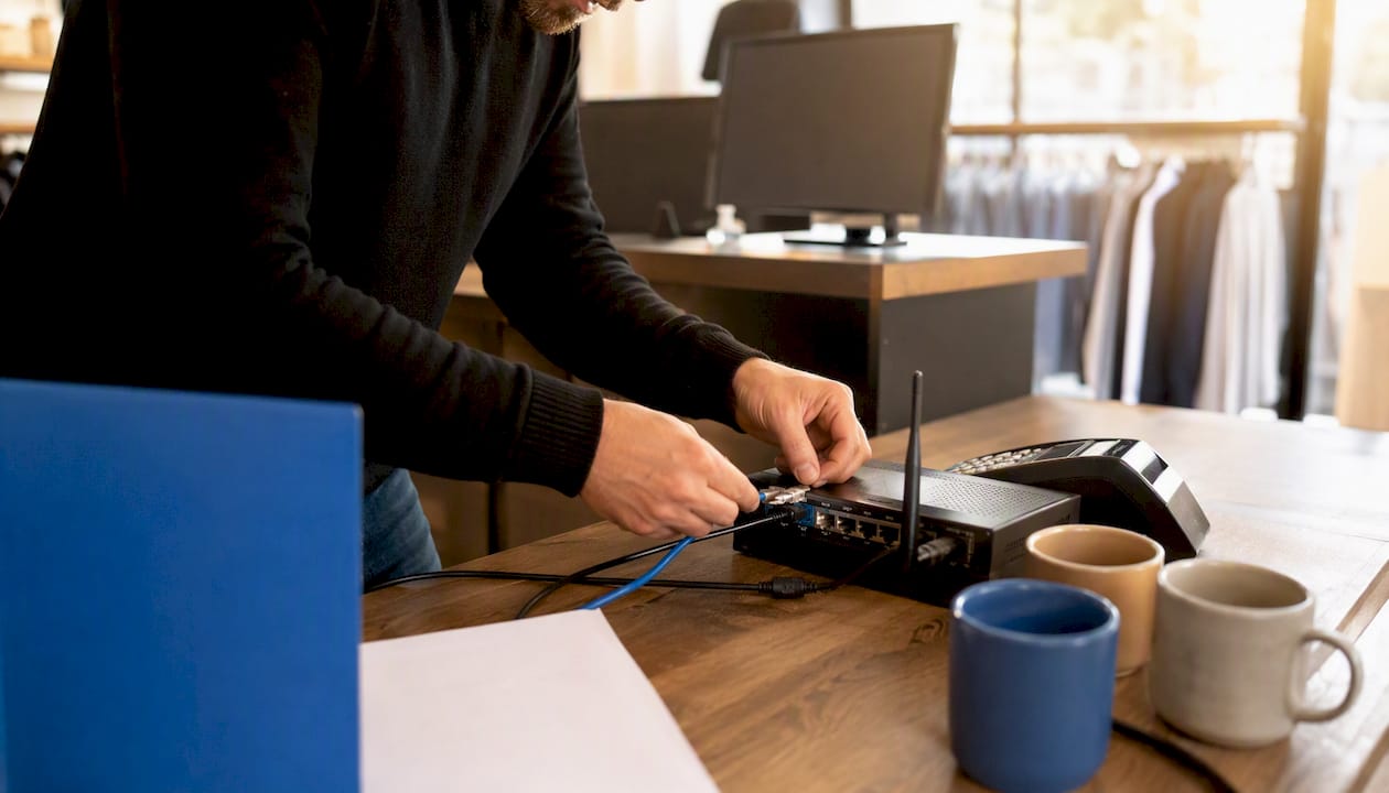 Hands restarting router near payment terminal