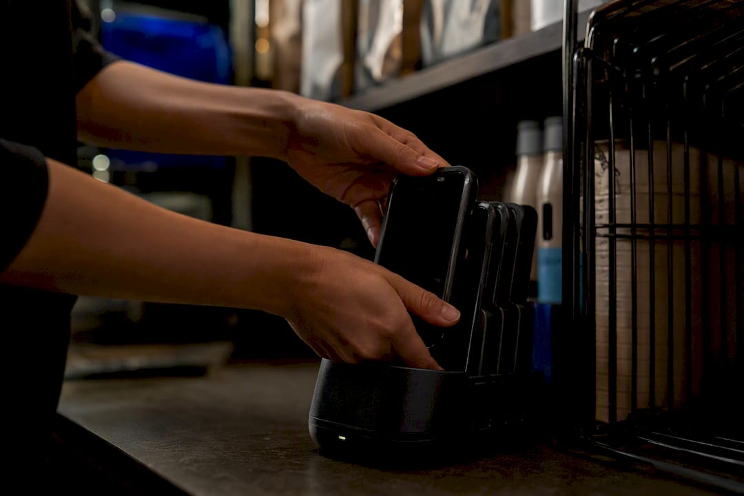 Hands charging handheld device in bar backroom